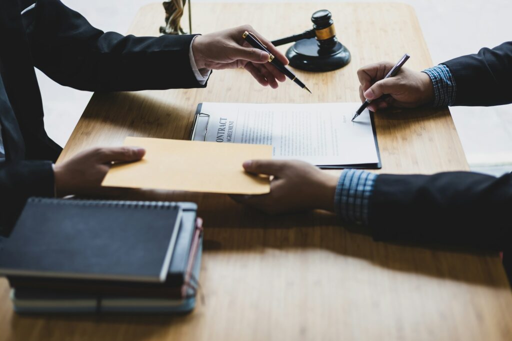 Businessman handing envelope to lawyer and signing contract, legal complaint and legal justice.